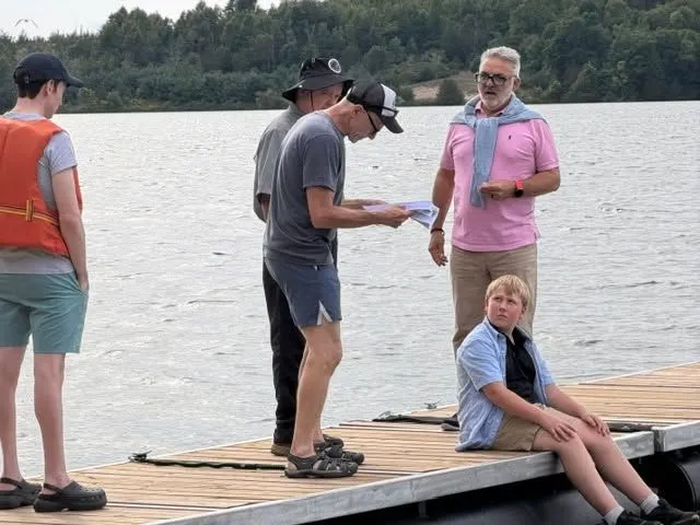 Cast and crew gathered on a dock between takes