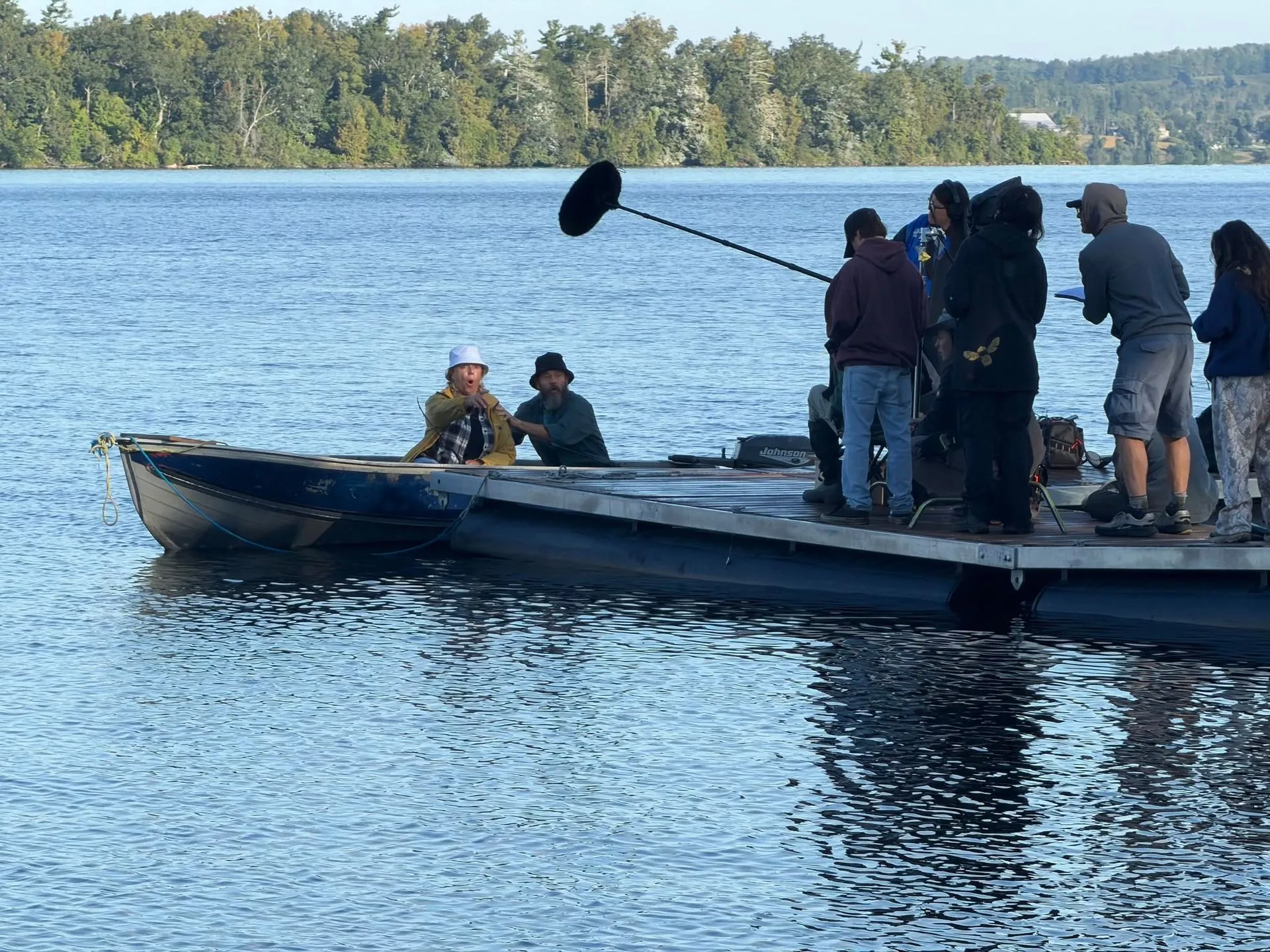 Film crew and boom microphone working beside a lake during a shoot